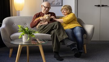 Two elderly person playing with a cat